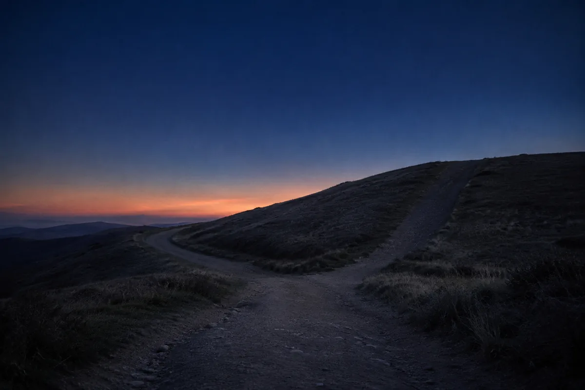 A dirt road climbing over a hill at twilight